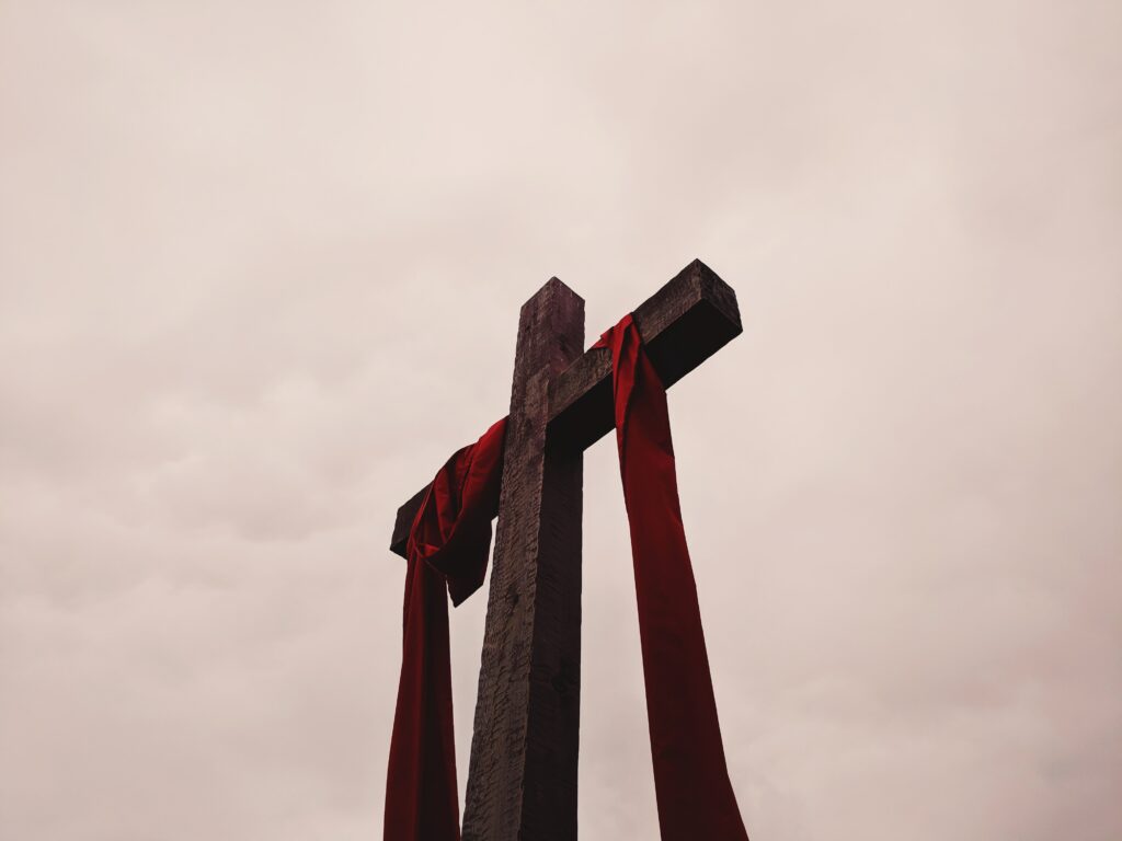 Photo of a cross, with red banner hanging down from it.