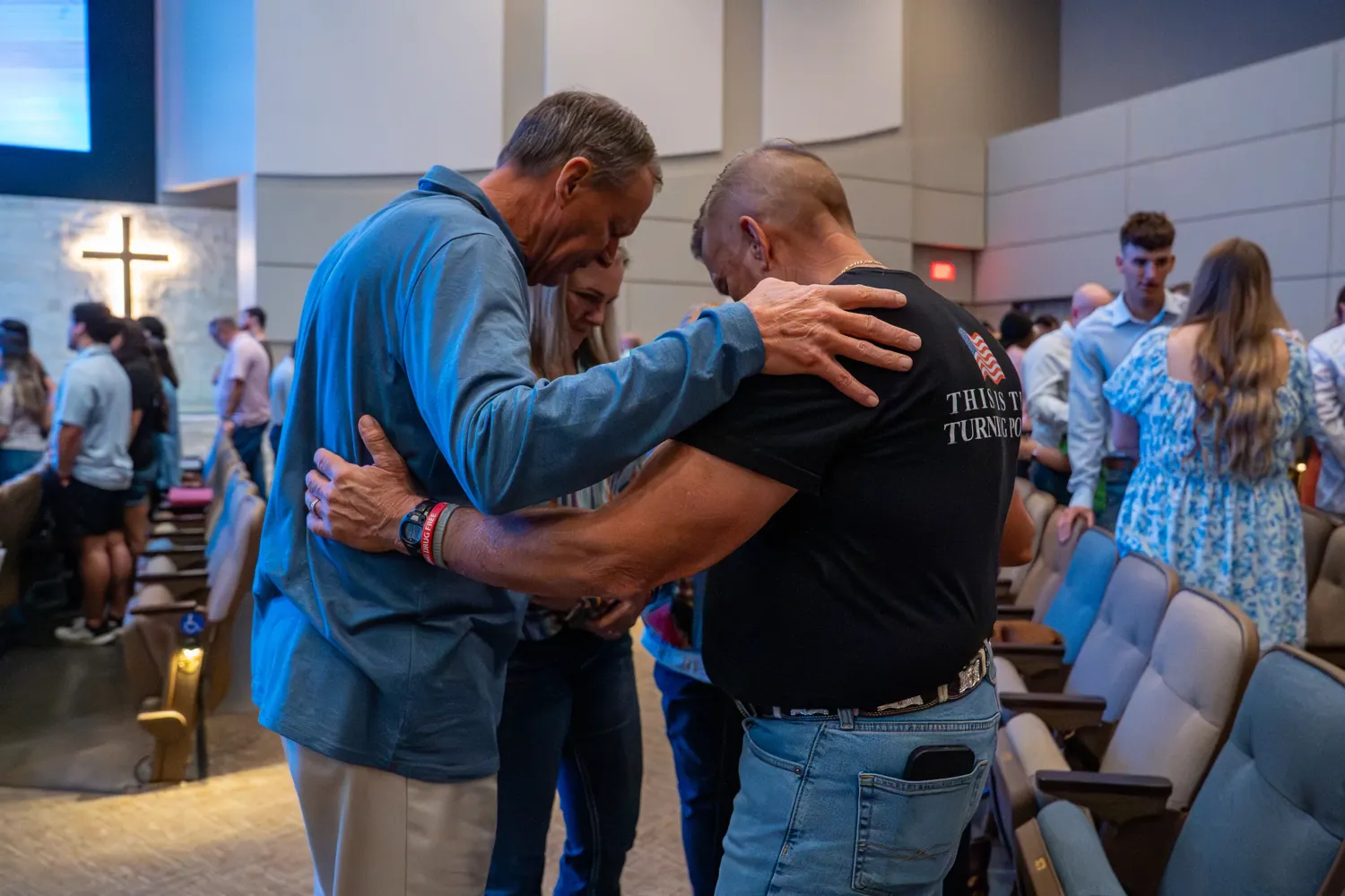 Church members praying together with hands on one another's shoulders