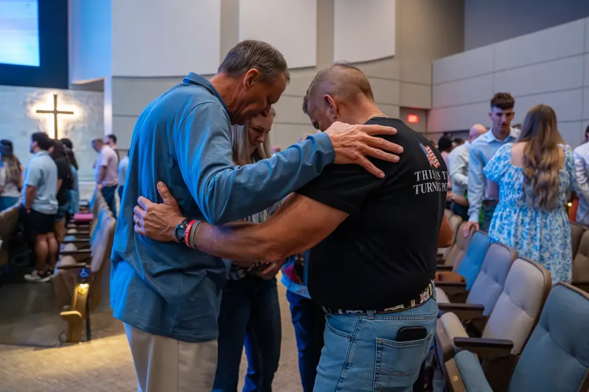 Church members praying together with hands on one another's shoulders